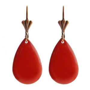 Peut inclure: Une paire de boucles d'oreilles en forme de larme rouge avec un crochet bronze et un dessus décoratif.