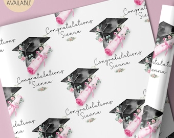 May include: White wrapping paper with a repeating pattern of graduation caps, diplomas, and floral accents. The text "Congratulations Sienna" is featured throughout the design. A matching card is available.