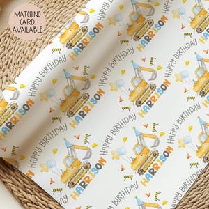 May include: White wrapping paper with a repeating pattern of yellow construction vehicles, balloons, and party hats. The text "HAPPY BIRTHDAY HARRISON" is printed in a playful font. A matching card is available.