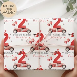 Luxury white personalized 1st birthday race car themed wrapping paper, featuring a watercolor red racing car with the number 1 on the side of it & a large number 1 with bunting & balloons and the wording 'Happy 1st Birthday' personalised with the child's name.