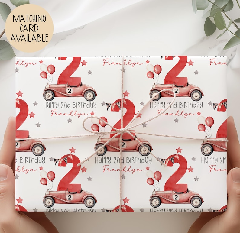 Luxury white personalized 1st birthday race car themed wrapping paper, featuring a watercolor red racing car with the number 1 on the side of it & a large number 1 with bunting & balloons and the wording 'Happy 1st Birthday' personalised with the child's name.
