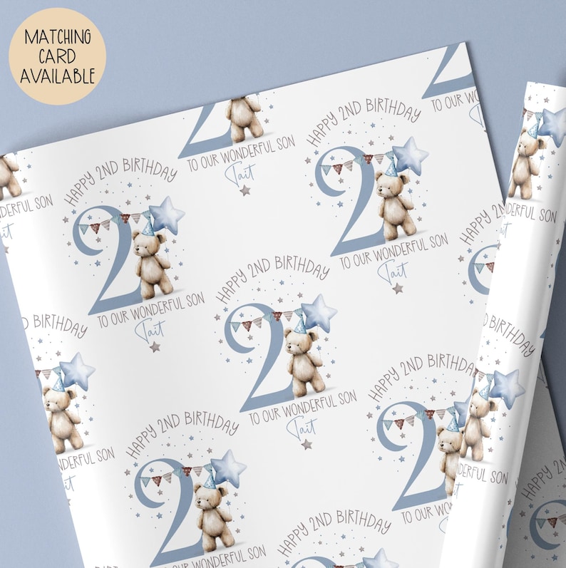 Luxury white personalised 2nd birthday wrapping paper, featuring a gorgeous teddy holding a blue star balloon standing next to a blue number 2 & matching bunting surrounded by little stars & the wording 'Happy 2nd Birthday to our wonderful Son/Grandson/Nephew, any relation' personalised with the child's name.
