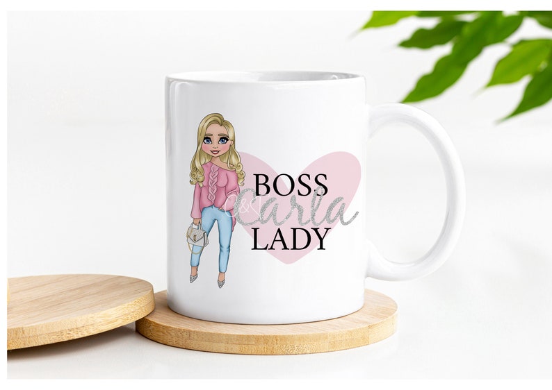 May include: White ceramic mug with a pink heart and the text "BOSS Carla LADY" in black and silver glitter. A cartoon illustration of a woman with blonde hair wearing a pink sweater and blue jeans is on the left side of the mug.
