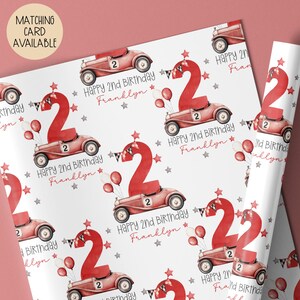Luxury white personalized 1st birthday race car themed wrapping paper, featuring a watercolor red racing car with the number 1 on the side of it & a large number 1 with bunting & balloons and the wording 'Happy 1st Birthday' personalised with the child's name.