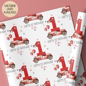 Luxury white personalized 1st birthday race car themed wrapping paper, featuring a watercolor red racing car with the number 1 on the side of it & a large number 1 with bunting & balloons and the wording 'Happy 1st Birthday' personalised with the child's name.