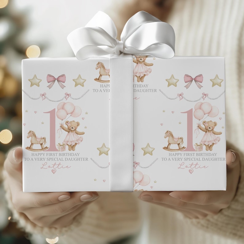 Personalised pink first birthday wrapping paper featuring a cute teddy bear in a tutu holding balloons, rocking horse, gold stars, pink bows, and the number one. Text reads “Happy First Birthday to a Very Special Daughter/Granddaughter/Any relation ” Ideal for baby girl’s first birthday gifts.