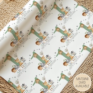 May include: White wrapping paper with a repeating pattern of a green number one, jungle animals, and the text "ARCHIE Happy 1st Birthday." The design includes giraffes, monkeys, zebras, and hedgehogs. A matching card is available.