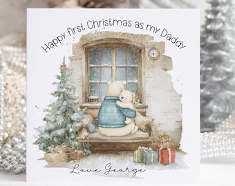 May include: A Christmas card with a watercolor illustration. It features two bears, one hugging the other, in front of a window. Text reads "Happy first Christmas as my Daddy" and "Love George". A Christmas tree and gifts are also depicted.