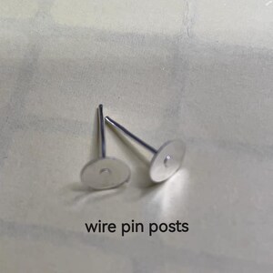 May include: Two silver-colored wire pin posts with flat, round disc tops. The posts are on a light-colored surface. The text "wire pin posts" is printed in black below the posts.