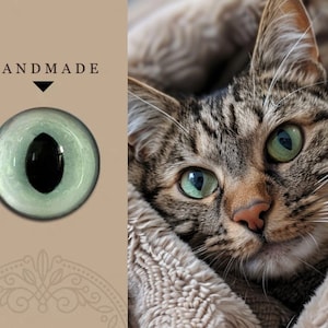 May include: Handmade glass cat eye with a green iris and black pupil. The eye is set against a brown background with the word "HANDMADE" in black text.