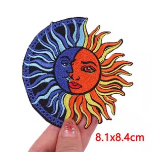 May include: Embroidered patch featuring a celestial design of the sun and moon. The sun half is orange and yellow, while the moon half is blue. The patch measures 8.1 x 8.4 cm.