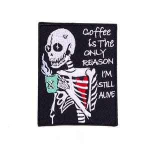 Peut inclure: Écusson brodé représentant un squelette tenant une tasse de café verte avec de la vapeur. Le patch porte l'inscription blanche "Coffee Is The Only Reason I'm Still Alive". Le squelette est blanc avec des accents rouges sur fond noir.