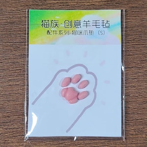 May include: A white card with a pink paw print outline and pink paw-shaped embellishments. The card has text in Chinese characters and is in a clear plastic sleeve. The top of the card has a gradient of yellow and green.