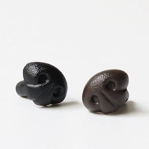 May include: Two plastic dog noses, one black and one brown, are displayed against a white background. The noses have a textured surface and are designed with nostril details. These are likely craft supplies or costume accessories.