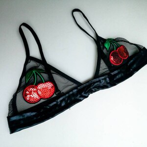 May include: Black mesh lingerie bra with red cherry embellishments.