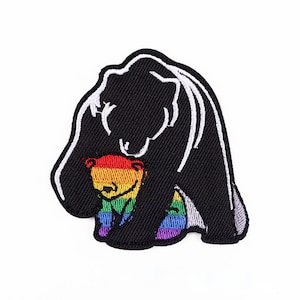 Puede incluir: Parche bordado que representa un oso negro abrazando a un osezno con los colores del arcoíris. El parche tiene un fondo negro con costuras blancas que delinean las figuras de los osos. El osezno arcoíris tiene una cara sonriente. Ideal para chaquetas, bolsos u otros artículos de tela.