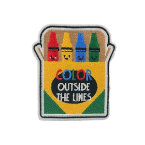 Puede incluir: Parche bordado con una caja de cuatro lápices de colores sonrientes, rojo, amarillo, azul y verde. El parche tiene el texto "COLOR OUTSIDE THE LINES" en una fuente lúdica, ideal para niños.
