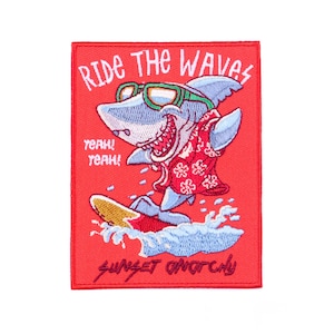 May include: Embroidered patch featuring a cartoon shark surfing. The shark wears sunglasses and a Hawaiian shirt, with the text "RIDE THE WAVES" and "SUNSET ANARCHY". The patch is red with blue, white, yellow, and gray accents.