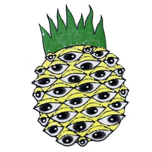 Może przedstawiać: Żółty ananas z zielonymi liśćmi, wykonany z cekinów, z czarnymi i białymi oczami pokrywającymi całą powierzchnię.