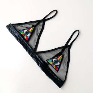 Könnte beinhalten: Schwarzer Mesh-Bralette mit zwei regenbogenfarbenen, gestickten Augen-Patches in Form von Dreiecken.
