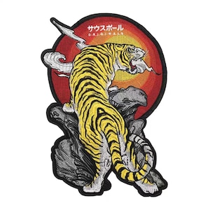May include: An embroidered iron-on patch featuring a yellow and black tiger with a red and orange sun behind it. The text "サウスポール" is written in black above the sun. The text "ORIGINALS" is written in black below the sun.
