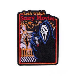 May include: Embroidered patch with a black background and a red border. The patch features the text "Let's watch Scary Movies" and an illustration of a ghost-faced figure holding a knife in front of a house.