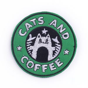 Könnte beinhalten: Grüner und weißer gestickter Aufnäher mit dem Text "Cats and Coffee" und einer Comic-Katze in einem Kreis.