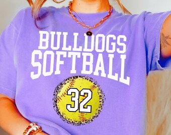 May include: Purple t-shirt with the text "Bulldogs Softball" and a yellow softball with the number 32 on it.