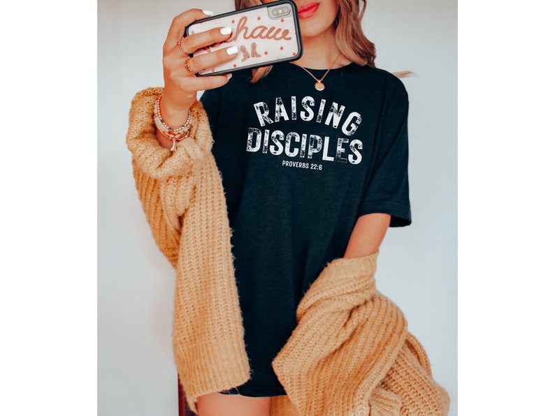 May include: Black t-shirt with white text that reads "Raising Disciples Proverbs 22:6".