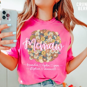 May include: Pink t-shirt with a floral design and the word "mama" in white script. The shirt has the names "Brandon, Lydia, Sam, Stephen, Maxwell" written below the floral design.