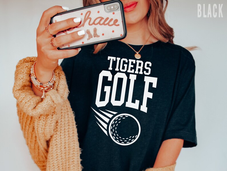 May include: Black t-shirt with white text that reads "TIGERS GOLF" and a white golf ball graphic.