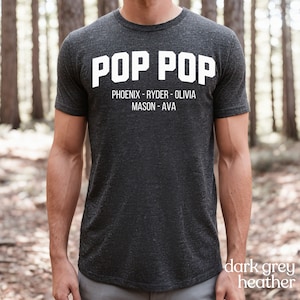 May include: Dark grey heather t-shirt with the text "POP POP" in white. Below the text are the names "PHOENIX - RYDER - OLIVIA MASON - AVA" in white.