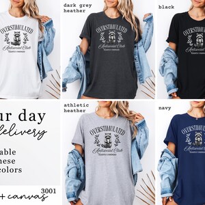 Puede incluir: Camisetas en blanco, gris oscuro, negro, gris deportivo y azul marino. Cada camiseta presenta el texto "OVERSTIMULATED Antisocial Club" con un gr&aacute;fico de mapache. Las camisetas est&aacute;n disponibles en cinco colores.