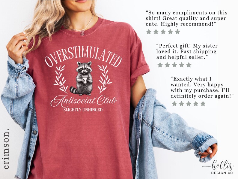 Puede incluir: Camiseta de color carmes&iacute; con la frase "OVERSTIMULATED Antisocial Club SLIGHTLY UNHINGED" y un dibujo de mapache. La camiseta es de cuello redondo y tiene un aspecto vintage. El dise&ntilde;o es blanco.