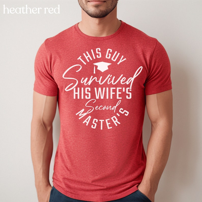 May include: Red heather t-shirt with white text that reads "This Guy Survived His Wife's Second Masters" with a graduation cap icon.