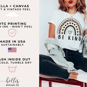 May include: White t-shirt with a rainbow graphic featuring a leopard print and black hearts. The rainbow has a small heart in the center and the text "BE KIND" below it.