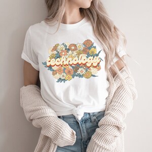 May include: White t-shirt with a retro-style graphic of the word "technology" surrounded by colorful flowers.