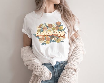 Op de afbeelding: Wit T-shirt met een retro-grafische afbeelding van het woord "technologie" omringd door kleurrijke bloemen.