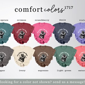 Puede incluir: Una colecci&oacute;n de camisetas Comfort Colors en varios colores, cada una con un gr&aacute;fico de mapache y el texto "It's fine. I'm fine." Los colores incluyen azul abeto, carmes&iacute;, crunchberry, mezclilla, violeta, pimienta, marfil, espresso, verde claro y sand&iacute;a.