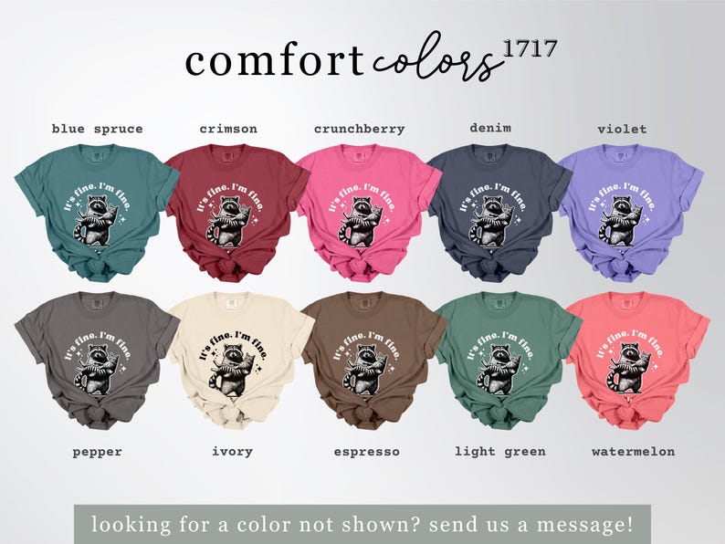Puede incluir: Una colecci&oacute;n de camisetas Comfort Colors en varios colores, cada una con un gr&aacute;fico de mapache y el texto "It's fine. I'm fine." Los colores incluyen azul abeto, carmes&iacute;, crunchberry, mezclilla, violeta, pimienta, marfil, espresso, verde claro y sand&iacute;a.