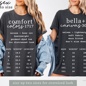 May include: Two dark grey unisex t-shirts with white text and size charts. One shirt reads "Comfort Colors 1717" and the other "bella + canvas 3001". The shirts have different fits and fabric types. The text "size up two sizes for oversized look" is at the bottom.