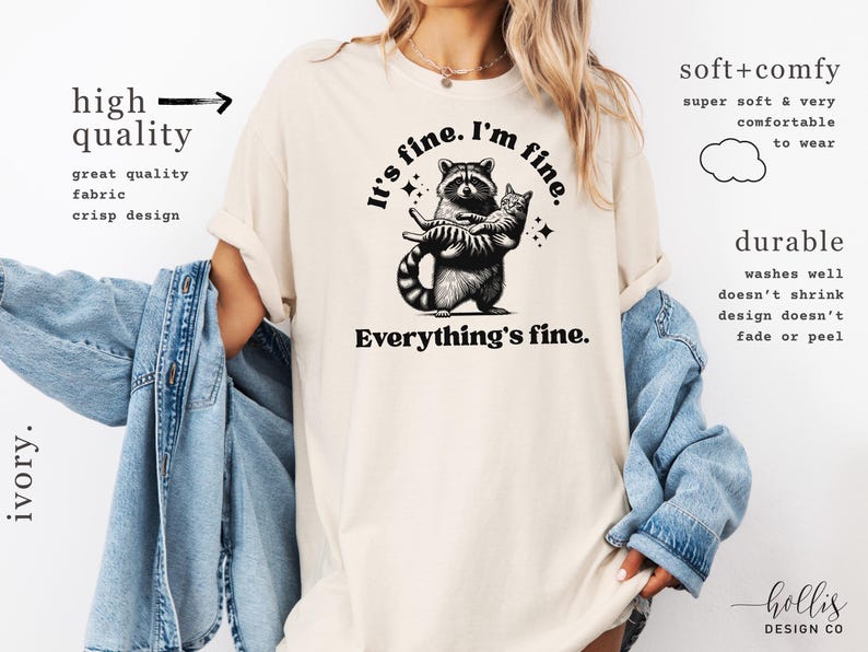 Puede incluir: Camiseta color marfil con un mapache abrazando a un gato, con el texto "It's fine. I'm fine. Everything's fine." La camiseta tambi&eacute;n tiene texto que dice "alta calidad" y "duradero".