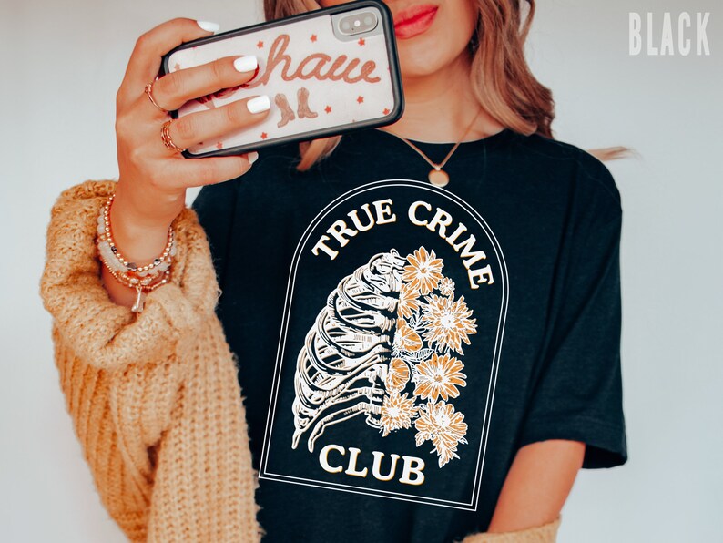 May include: Black t-shirt with a white graphic of a ribcage with flowers and the text "True Crime Club".