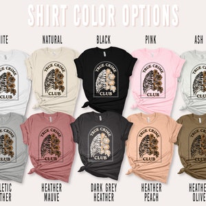 May include: A variety of t-shirt colors with a graphic design of a ribcage with sunflowers and the text "True Crime Club". The colors include white, natural, black, pink, ash, athletic heather, heather mauve, dark grey heather, heather peach, and heather olive.