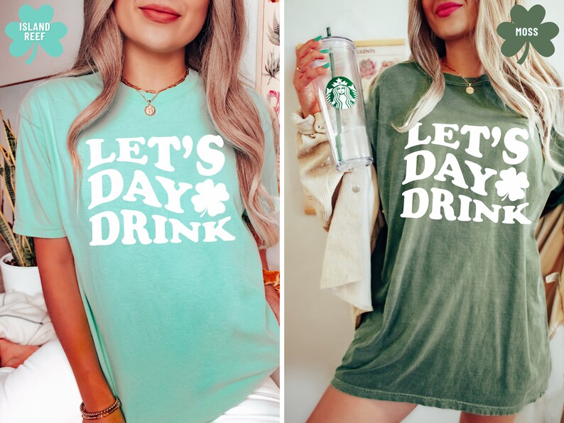 May include: Two women wearing green t-shirts with the text "Let's Day Drink" and a shamrock graphic. The t-shirt on the left is a light green color and the t-shirt on the right is a dark green color.