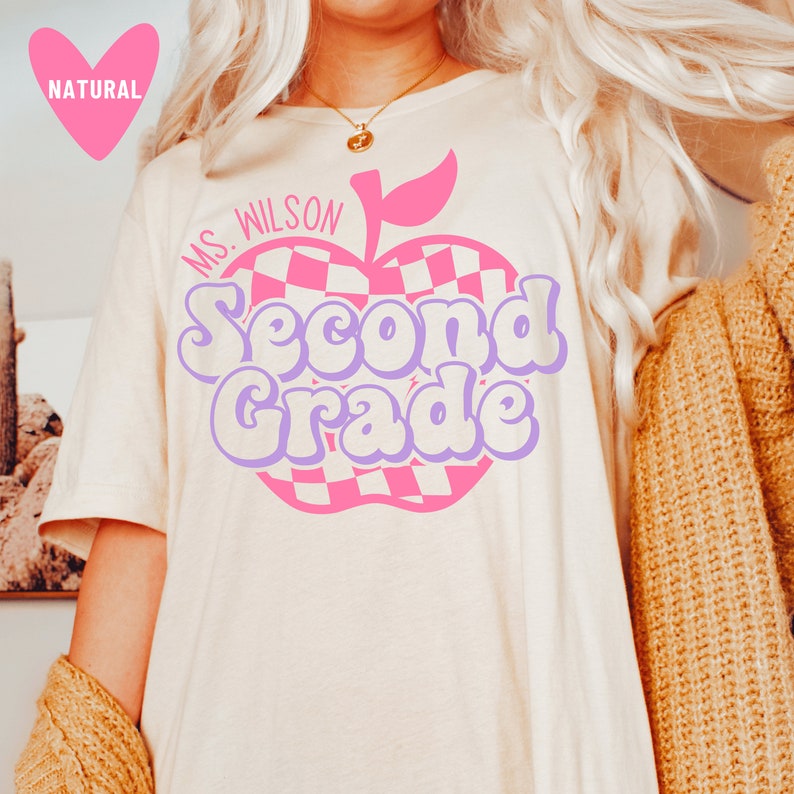 May include: A white t-shirt with a pink and purple apple graphic that says "Ms. Wilson Second Grade".