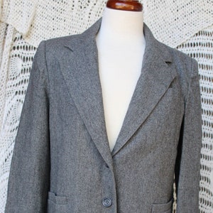 May include: A gray blazer with a single button closure and two pockets. The blazer is made of a textured fabric.
