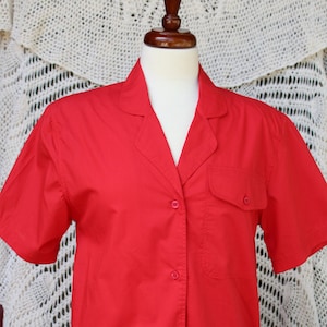 May include: A red short-sleeved button-down shirt with a single chest pocket.