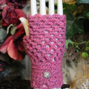 May include: Pink crocheted fingerless gloves with a pearl-like button on the wrist.