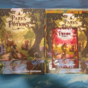 May include: A board game box set titled "Parks & Potions" with a colorful illustration of forest animals and a person. The box is open, revealing the game components and a smaller box titled "Potion Perils".